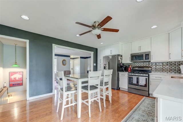 713 Settler Rd, Fenton, MO 63026 - kitchen featuring appliances with stainless steel finishes, a ceiling fan, white cabinets, light wood-type flooring, and tasteful backsplash