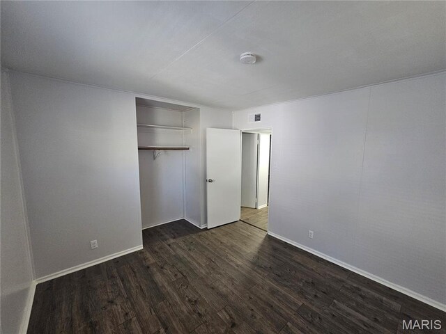 1150 Lilac Dr, Belleville, IL 62220 - unfurnished bedroom with dark wood-type flooring, a closet, and baseboards