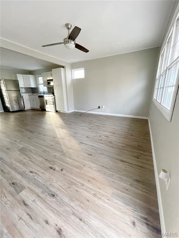 913 N 38th St, Belleville, IL 62226 - unfurnished living room featuring baseboards, light wood-style floors, and a ceiling fan