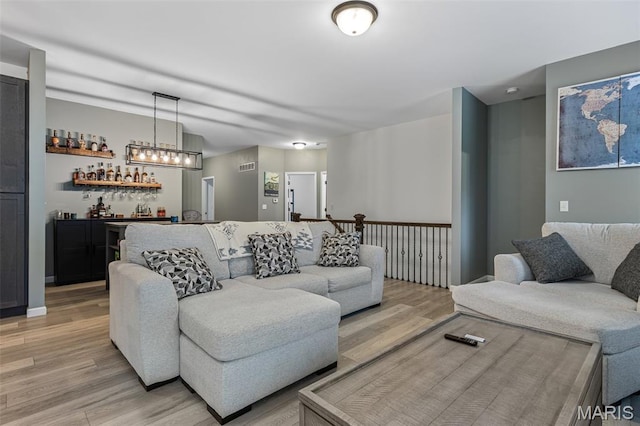 living room featuring bar area and light wood-style flooring
