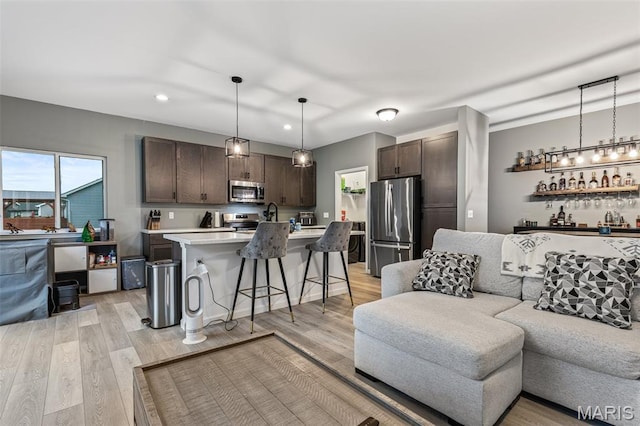 living area with recessed lighting, light wood finished floors, and bar area