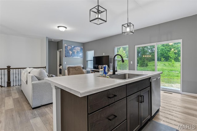 kitchen featuring a sink, light countertops, stainless steel dishwasher, and light wood-type flooring