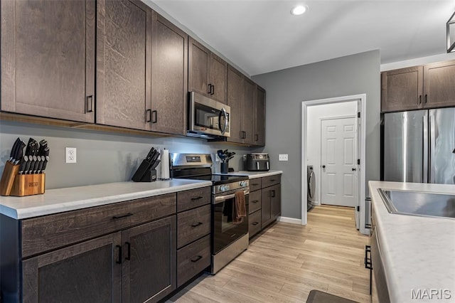 kitchen with stainless steel appliances, dark brown cabinets, light wood finished floors, light countertops, and recessed lighting