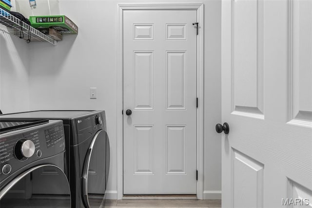 washroom with washer and clothes dryer, light wood-style floors, and baseboards