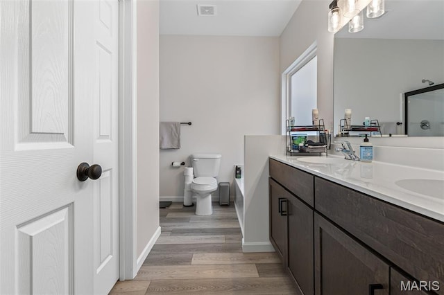 bathroom featuring double vanity, wood finished floors, baseboards, toilet, and a shower