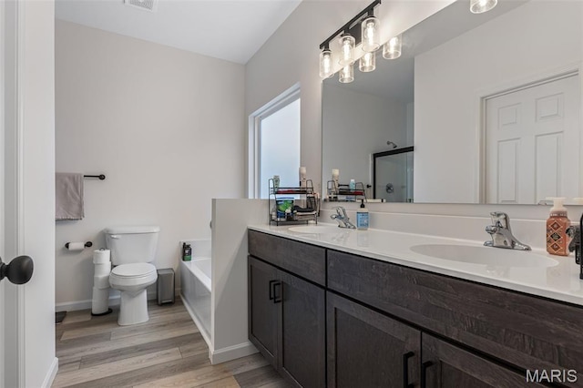 full bath with wood finished floors, double vanity, toilet, a shower with shower door, and a garden tub