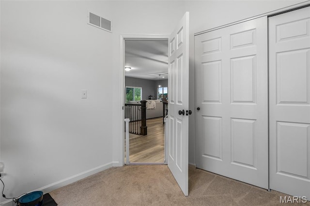 hallway featuring light carpet and baseboards