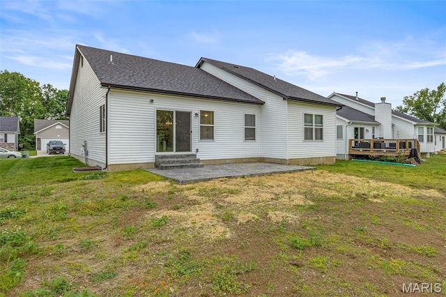 back of property with a lawn, a wooden deck, a patio area, entry steps, and a shingled roof