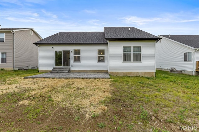 rear view of property featuring a yard, roof with shingles, and entry steps