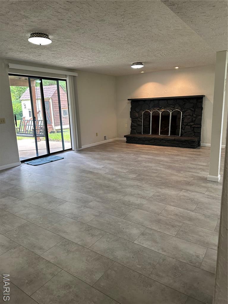 305 Berkshire Dr, Belleville, IL 62223 - unfurnished living room with a stone fireplace and a textured ceiling
