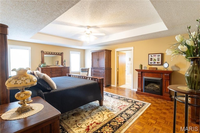 103 Woodland Ln, Saint Robert, MO 65584 - bedroom with a tray ceiling, a textured ceiling, a fireplace, and ceiling fan