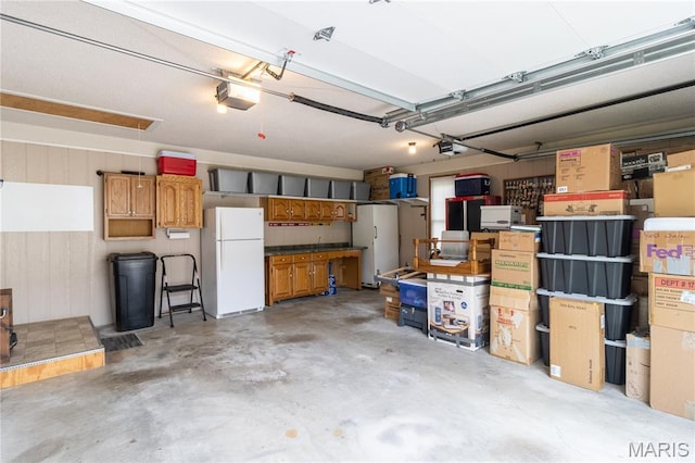 103 Woodland Ln, Saint Robert, MO 65584 - garage featuring freestanding refrigerator, a garage door opener, and wooden walls