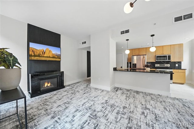 314 N Broadway Unit 806, Saint Louis, MO 63102 - kitchen featuring appliances with stainless steel finishes, dark countertops, open floor plan, decorative light fixtures, and baseboards