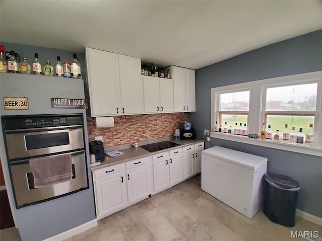 201 E Main St, Lewistown, MO 63452 - kitchen with refrigerator, decorative backsplash, stainless steel double oven, black electric stovetop, and white cabinetry