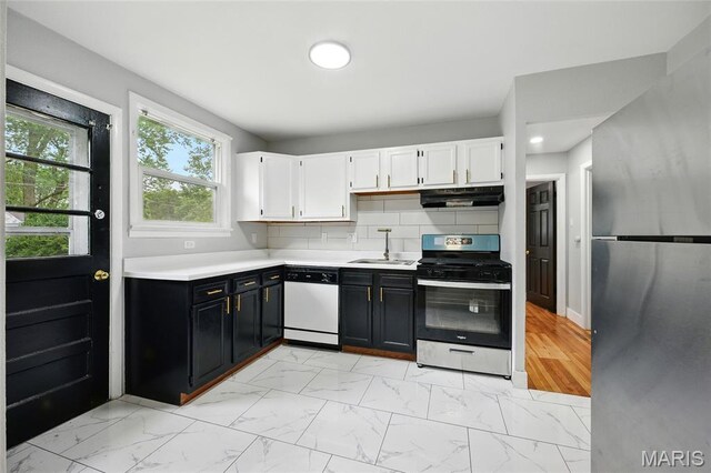 1005 Edgehill Dr, Ferguson, MO 63135 - kitchen with appliances with stainless steel finishes, under cabinet range hood, light countertops, light marble finish flooring, and dark cabinets