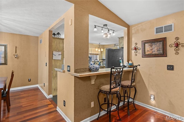 818 Sheraton Ln, Herculaneum, MO 63048 - kitchen with freestanding refrigerator, dark wood finished floors, a breakfast bar, baseboards, and a peninsula