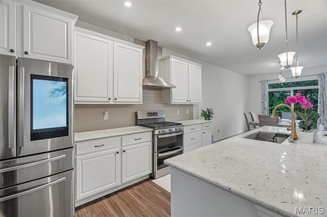 708 Kenmare Ct, Ofallon, MO 63368 - kitchen featuring stainless steel appliances, wall chimney exhaust hood, a sink, tasteful backsplash, and white cabinetry