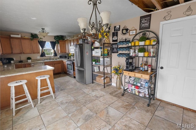 806 Erika Leigh Ct, Caseyville, IL 62232 - kitchen featuring stainless steel appliances, light countertops, brown cabinetry, a peninsula, and a breakfast bar area