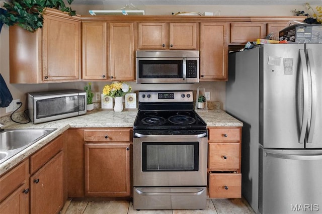 806 Erika Leigh Ct, Caseyville, IL 62232 - kitchen with appliances with stainless steel finishes, light countertops, brown cabinets, and light tile patterned flooring