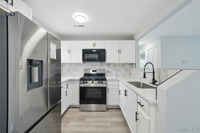 260 S Hartnett Ave, Saint Louis, MO 63135 - kitchen featuring appliances with stainless steel finishes, light wood-type flooring, white cabinets, backsplash, and a peninsula