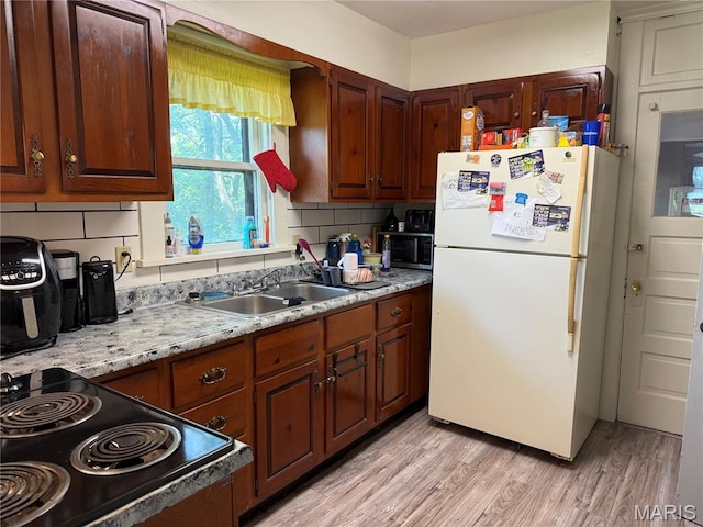 111 N Levering Ave, Hannibal, MO 63401 - kitchen with freestanding refrigerator, a sink, range, light countertops, and light wood-style floors