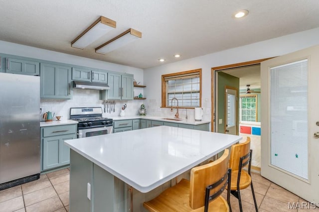 25350 Englewood Ln, Lebanon, MO 65536 - kitchen with appliances with stainless steel finishes, under cabinet range hood, a sink, light countertops, and backsplash