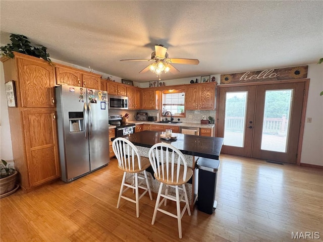 3581 Eagle Crest Dr, Palmyra, MO 63461 - kitchen with appliances with stainless steel finishes, a sink, light wood-style flooring, a ceiling fan, and a textured ceiling