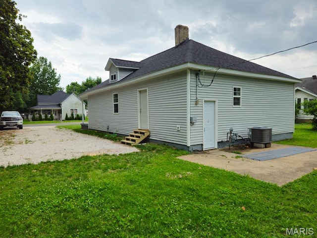 308 E Kathleen, Sikeston, MO 63801 - back of property with entry steps, cooling unit, a yard, a chimney, and a shingled roof