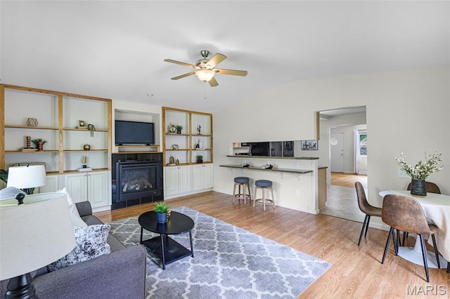 1385 Mallard Ln, Florissant, MO 63031 - living area featuring vaulted ceiling, ceiling fan, light wood-style flooring, and a glass covered fireplace