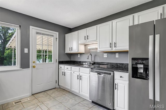12006 Glengrove Dr, Maryland Heights, MO 63043 - kitchen featuring appliances with stainless steel finishes, white cabinetry, light tile patterned flooring, dark stone countertops, and a textured ceiling
