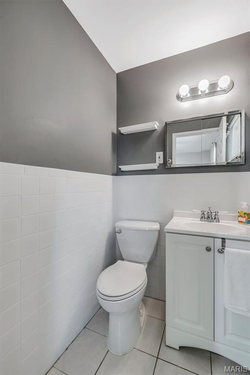 12006 Glengrove Dr, Maryland Heights, MO 63043 - bathroom featuring vanity, tile patterned floors, tile walls, and a wainscoted wall