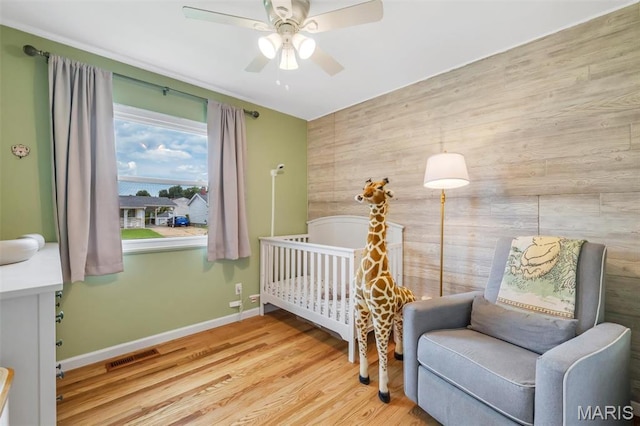 12006 Glengrove Dr, Maryland Heights, MO 63043 - bedroom featuring wood finished floors, wooden walls, a crib, and a ceiling fan