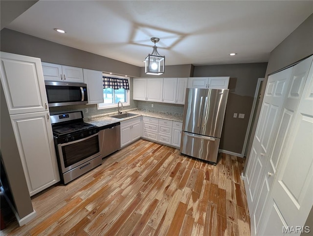 326 S Elm St, Bethalto, IL 62010 - kitchen with stainless steel appliances, tasteful backsplash, white cabinetry, light wood-style floors, and a sink