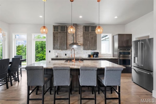 22206 Tree Farm Rd, Hermann, MO 63383 - kitchen with stainless steel appliances, wall chimney range hood, dark brown cabinets, tasteful backsplash, and light stone countertops