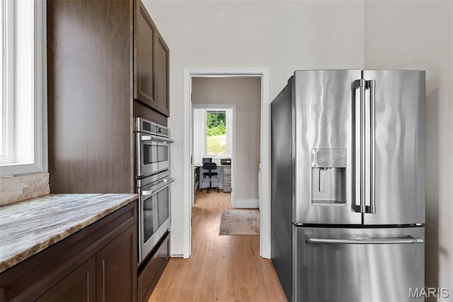 22206 Tree Farm Rd, Hermann, MO 63383 - kitchen featuring appliances with stainless steel finishes, dark brown cabinets, light wood-style flooring, and light stone countertops