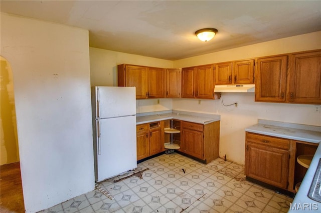 33974 Irish Ln, Brighton, IL 62012 - kitchen with freestanding refrigerator, under cabinet range hood, brown cabinets, and arched walkways