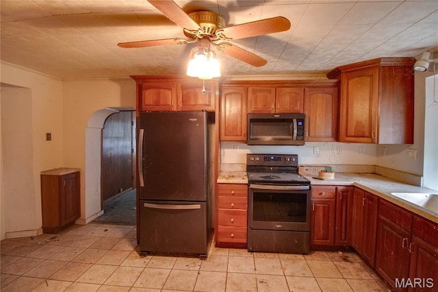 33425 Irish Ln, Brighton, IL 62012 - kitchen with appliances with stainless steel finishes, light countertops, ceiling fan, arched walkways, and brown cabinets