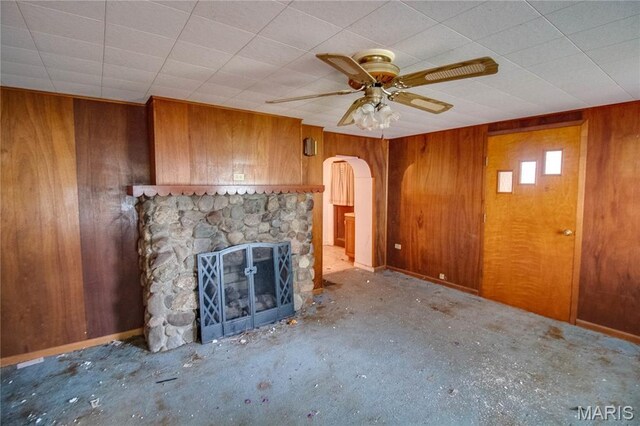 33425 Irish Ln, Brighton, IL 62012 - unfurnished living room with arched walkways, wood walls, ceiling fan, and a fireplace