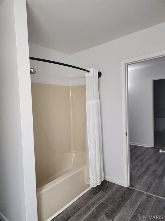 108 Auburn Dr, Waynesville, MO 65583 - full bathroom featuring wood finished floors, baseboards, and shower / bath combo with shower curtain