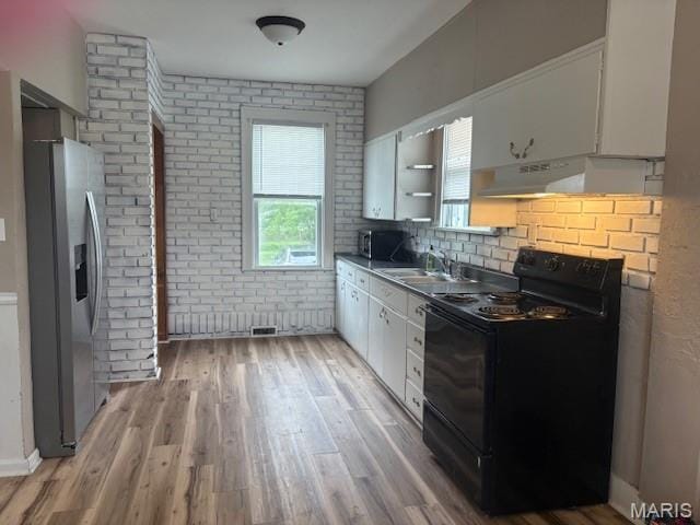 10303 Lincoln Trl, Fairview Heights, IL 62208 - kitchen featuring stainless steel appliances, under cabinet range hood, white cabinetry, light wood finished floors, and brick wall