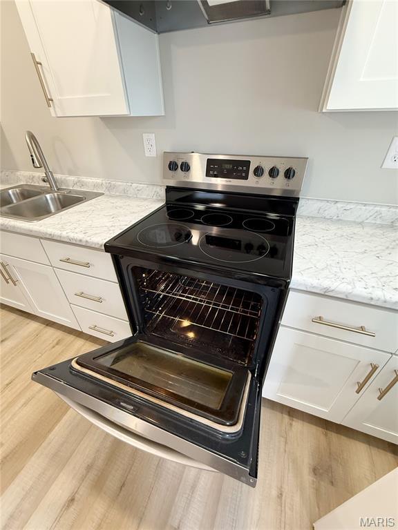 604 N Henderson St Unit A & B, Salem, MO 65560 - kitchen view of stainless steel electric range oven, a sink, light wood-style flooring, and white cabinets