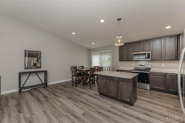 424 Triathlon Dr, Foristell, MO 63348 - kitchen with appliances with stainless steel finishes, wood finished floors, light countertops, recessed lighting, and a kitchen island