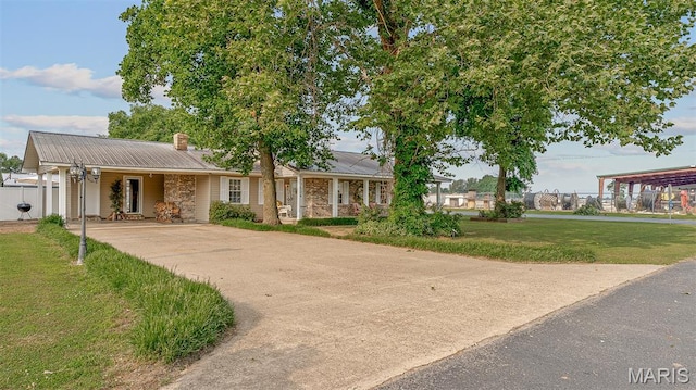 17504 Division St, Kennett, MO 63857 - view of front of property featuring concrete driveway, metal roof, a chimney, and a carport