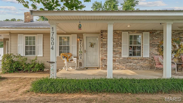 17504 Division St, Kennett, MO 63857 - doorway to property with covered porch, a chimney, and metal roof