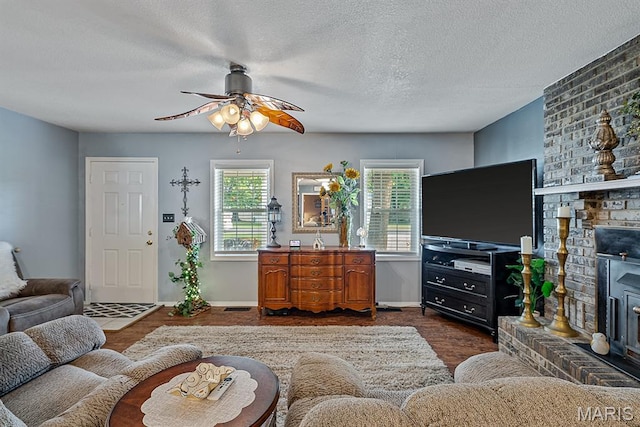 17504 Division St, Kennett, MO 63857 - living area featuring dark wood-style flooring, a ceiling fan, a wood stove, a textured ceiling, and baseboards
