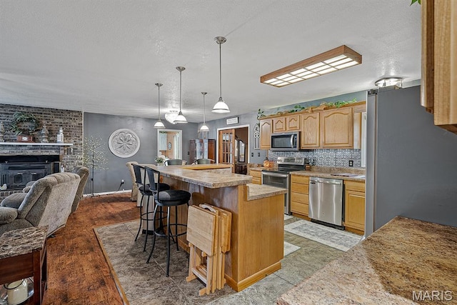 17504 Division St, Kennett, MO 63857 - kitchen with appliances with stainless steel finishes, open floor plan, a kitchen breakfast bar, a kitchen island, and light countertops