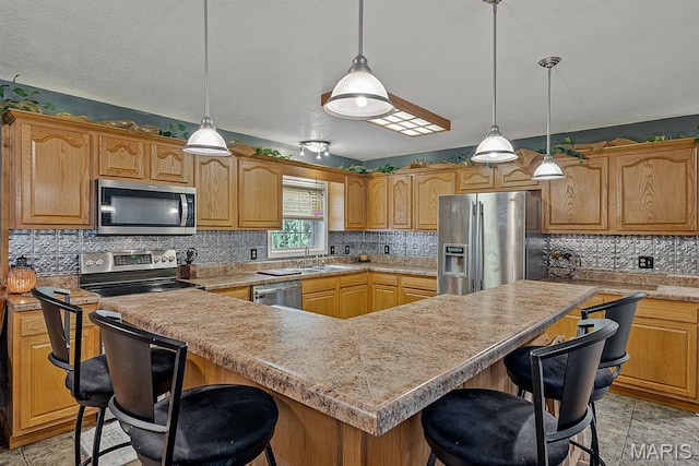 17504 Division St, Kennett, MO 63857 - kitchen featuring stainless steel appliances, a sink, a breakfast bar, backsplash, and a kitchen island