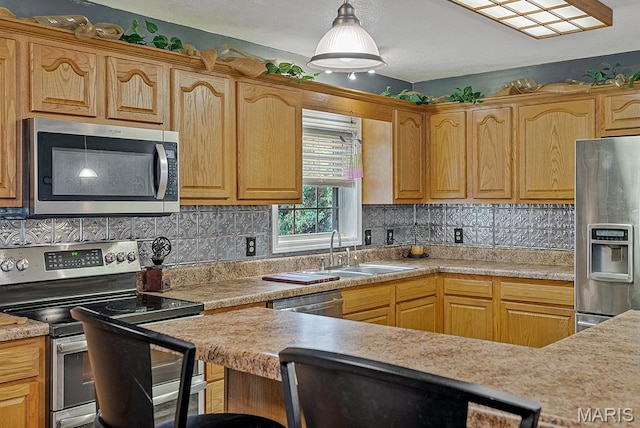17504 Division St, Kennett, MO 63857 - kitchen featuring stainless steel appliances, a sink, light countertops, backsplash, and hanging light fixtures
