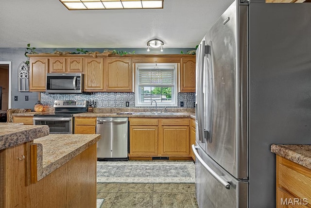 17504 Division St, Kennett, MO 63857 - kitchen featuring stainless steel appliances, a sink, decorative backsplash, and brown cabinets