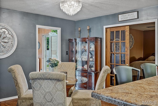 17504 Division St, Kennett, MO 63857 - dining area with a chandelier, a textured ceiling, wood finished floors, and baseboards